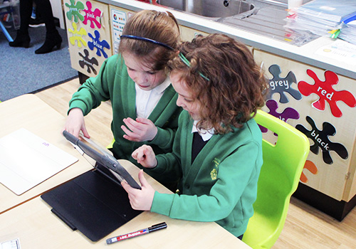 Two young girls using iPad in class