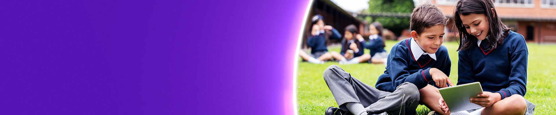 Two pupils on tablet on school field
