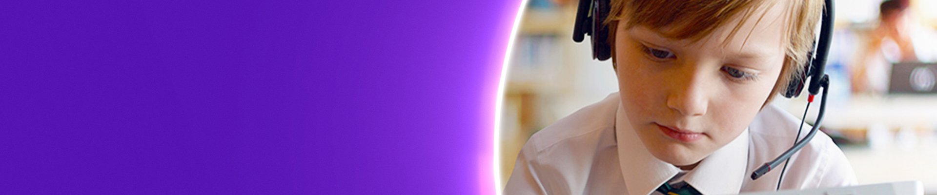 Boy in school uniform using a tablet device in a classroom