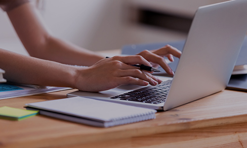 Male student in iniform using laptop device in classroom