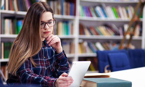 Student using electronic tablet in the school library 