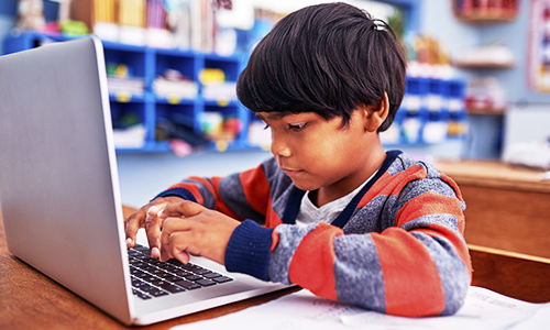 Male student using mobile device in classroom