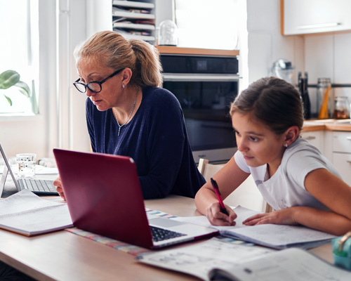 A young girl doing homework with her mum in her kitchen